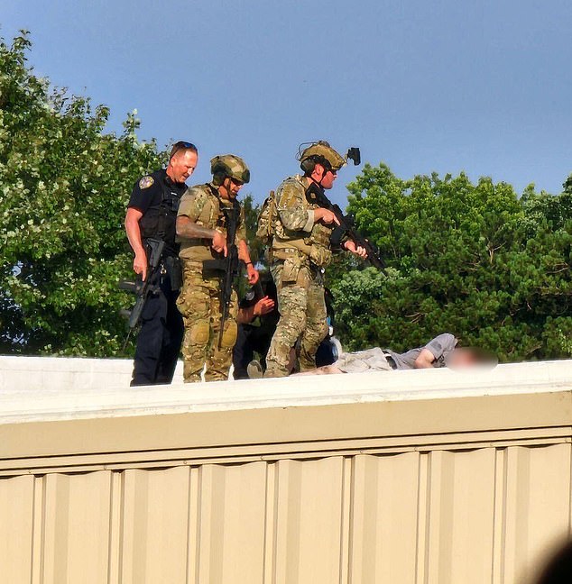 Security personnel stand over the body of the shooter on a rooftop near the Trump rally. Cheatle said he did not send officers to that roof because of its slope and the safety concerns posed by such a surface.