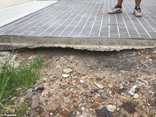 Homes are believed to be sinking throughout the area because they were built on flood-prone land and have poor foundations because they were built on insufficiently compacted landfill (pictured, a driveway with exposed concrete slab in Jordan Springs East, 2020).