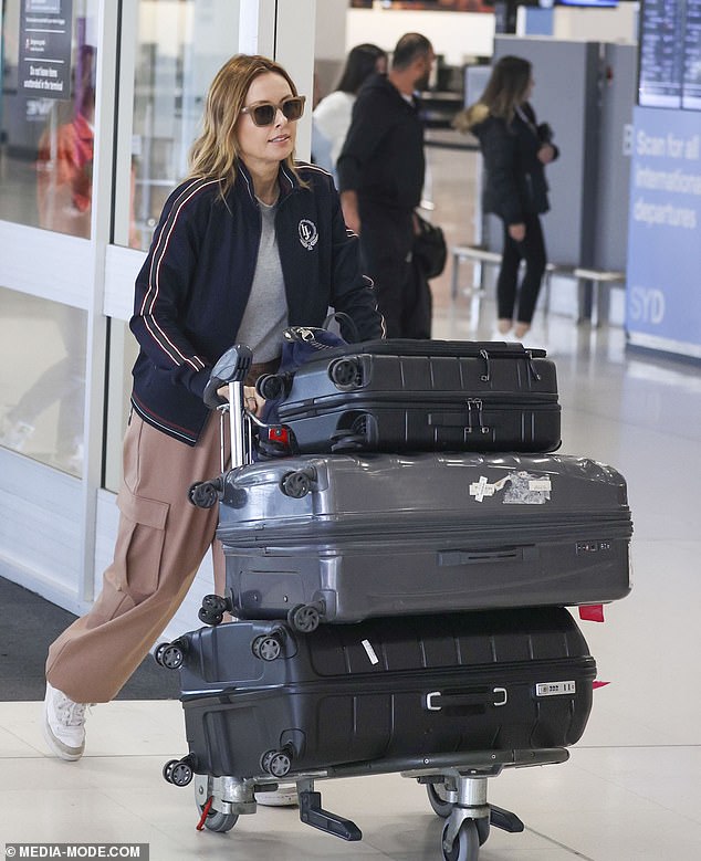 She completed her look with brown trousers and white sneakers, complemented by stylish sunglasses, and looked focused as she pushed her luggage through the bustling terminal.