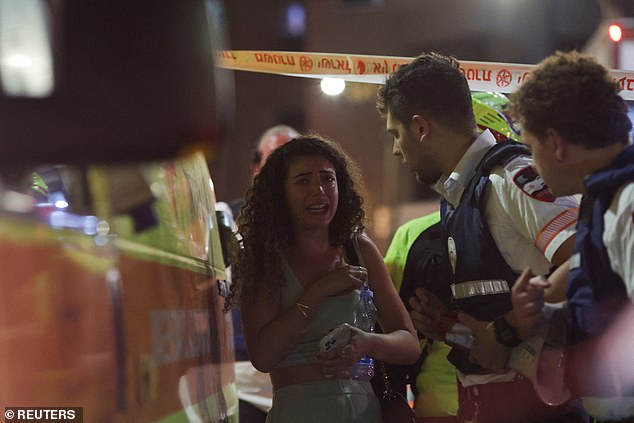 Emergency personnel assist a woman at the site of the explosion in Tel Aviv