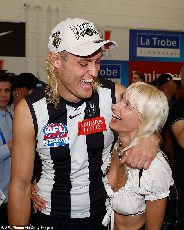 The pair are pictured celebrating in the changing room after Moore captained Collingwood to a grand final victory last year.