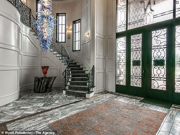 The front foyer features an interesting blue chandelier and a spiral staircase.