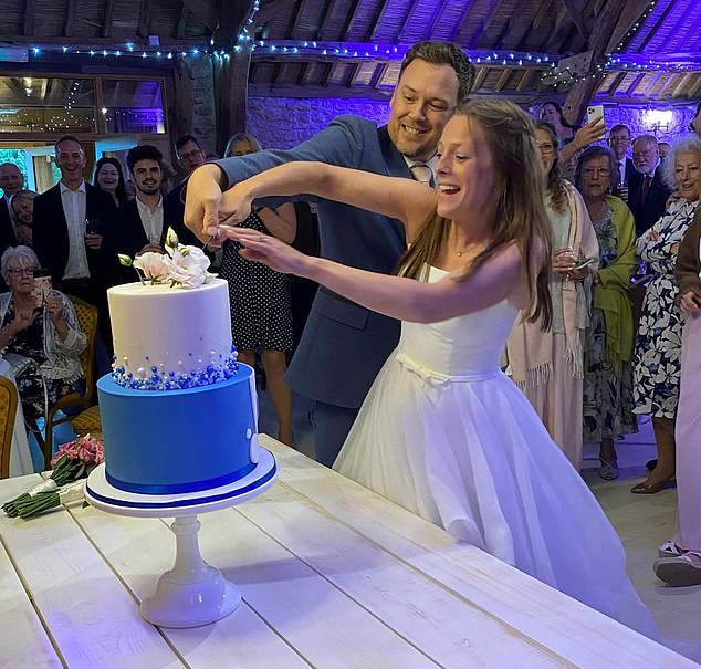 Elizabeth and David Slade are pictured on their wedding day, cutting the cake.