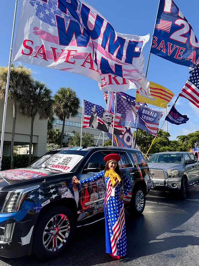 A Trump supporter poses next to an SUV decorated with political messages and flags on the back