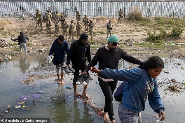 The Texas National Guard conducts an operation using non-lethal weapons, specifically a pepper spray gun, to disperse migrants who are maintaining a camp inside the Rio Grande on the border between Mexico and the United States in Ciudad Juarez,