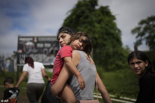 Venezuelan migrant Naiber Zerpa holds her son Mathias Marquez as they arrive at a temporary camp after walking across the Darien Gap from Colombia