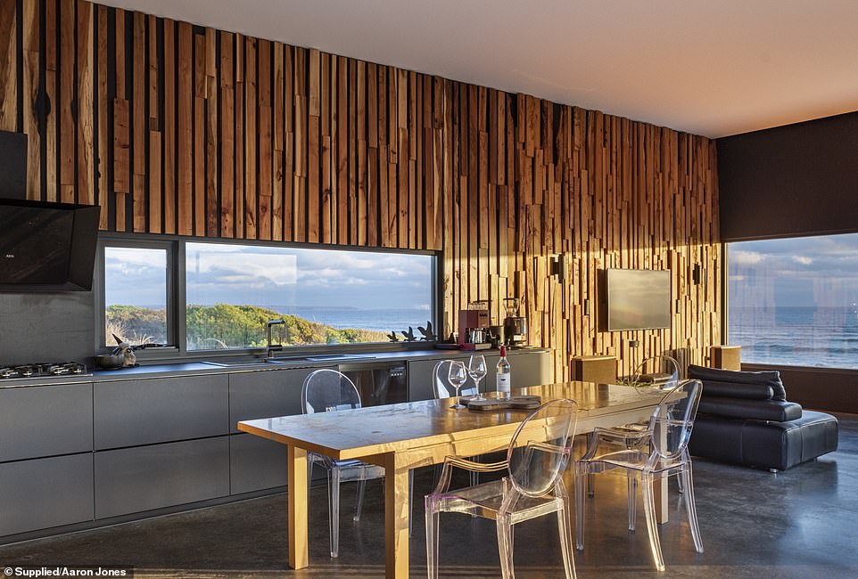 The spacious modern kitchen with sleek concrete floors is finished with black and stainless steel accents and opens to a mesmerizing ocean view.