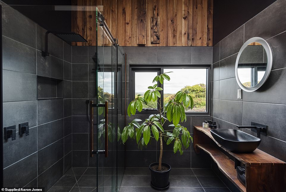 The spa-like bathroom offers stunning views and natural wood details.