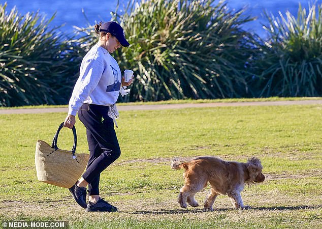 The actress kept warm in a grey jumper and black sweatpants as she enjoyed a cup of coffee while her dog ran through the park.