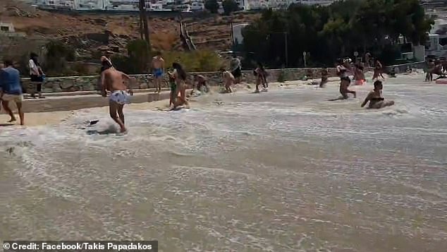 Bathers are seen running to escape the wave while others were caught in the shocking surge of water.