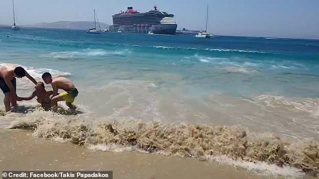 Two young men are seen running to help a woman who was caught in the giant wave