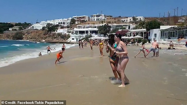 Children and their parents are seen running away from the huge wave, while other shocked bathers look on.