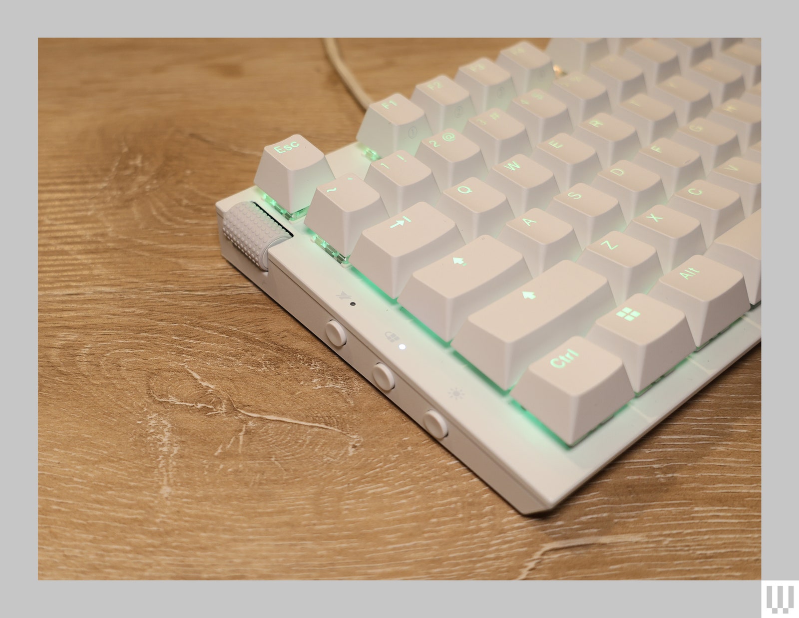 Close-up of left side of white computer keyboard with illuminated keys and a wheel on the top left