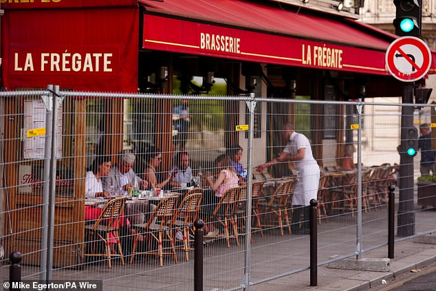 Locals were seen eating at a restaurant behind a perimeter fence in Paris that is being used as a first line of defence.