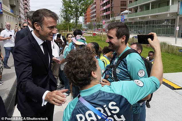 French President Emmanuel Macron poses for a selfie with volunteers as he visits the Olympic Village, at the 2024 Summer Olympics, Monday, July 22, 2024, in Paris.