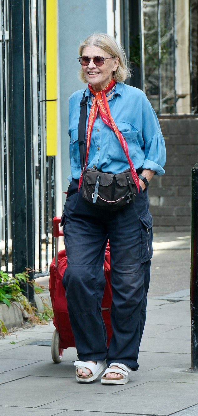 The Doctor Zhivago star accessorised her fashionable look with a red scarf and tortoiseshell sunglasses, pulling a trolley behind her as she made her way to the dry cleaners.