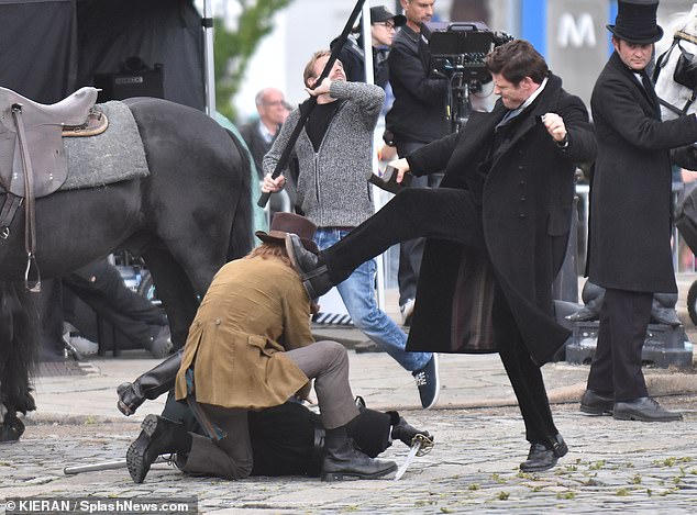 James looked furious as he was seen holding a piece of metal while swinging his arm in the air before going to kick his co-star who was lying on the road.