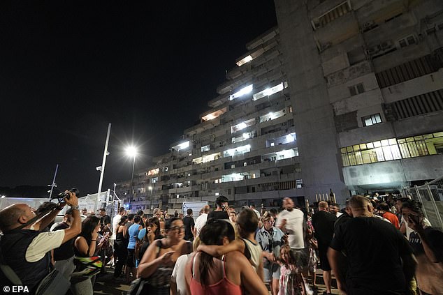 People who were evacuated from their apartments look at the collapse of a balcony in the Vela Celeste housing complex in Scampia, Naples