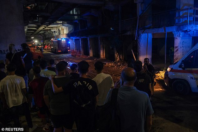 People wait outside the site of a balcony collapse in Naples, Italy. Mayor Gaetano Manfredi said Tuesday that social services had been sent to the scene to help residents.