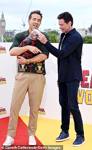 Peggy is seen in her superhero costume being adored by Reynolds and Jackman.