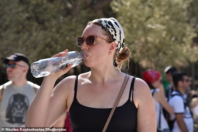 A tourist drinks water to cool off while visiting the Acropolis as a prolonged heatwave hits Athens, July 21, 2024