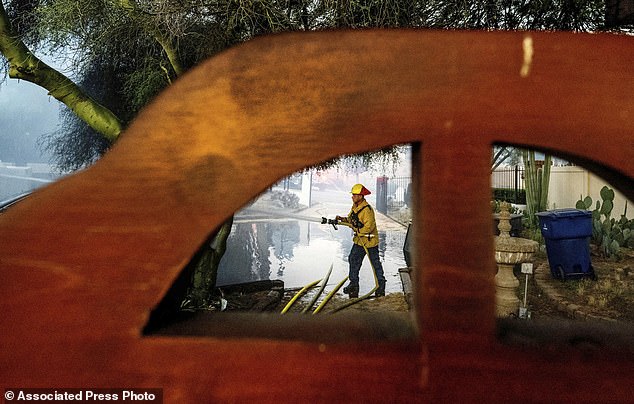 A firefighter hoses down the garage of a home that was destroyed by the Hawarden Fire in Riverside, California, Sunday, July 21, 2024.