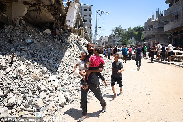 A man carries children as people inspect the damage following Israeli shelling in al-Bureij refugee camp in the central Gaza Strip, July 23, 2024.