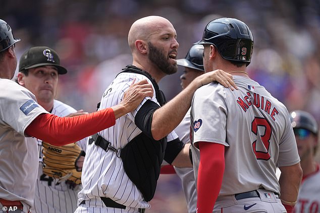 Colorado Rockies catcher Jacob Stallings, center, stands between starting pitcher Cal Quantrill, left, and Boston Red Sox's Reese McGuire.