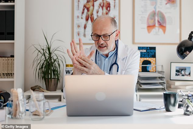 A doctor on a video call with a patient while sitting in his office (stock image)