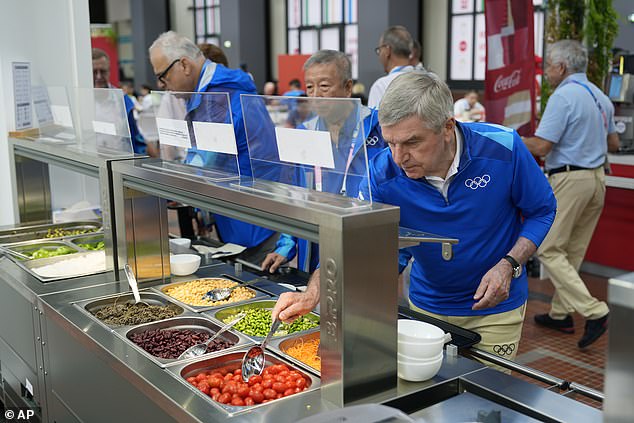 IOC President Thomas Bach samples food from a salad bar as he tours the Olympic Village ahead of the 2024 Summer Olympics on Monday.