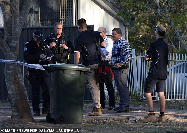 Officers and detectives are seen speaking with plumbers after repair work was completed.