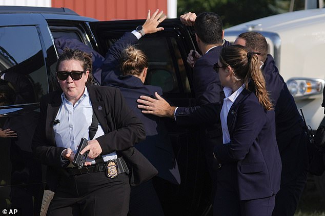 Republican presidential candidate and former President Donald Trump is covered by U.S. Secret Service agents at a campaign rally