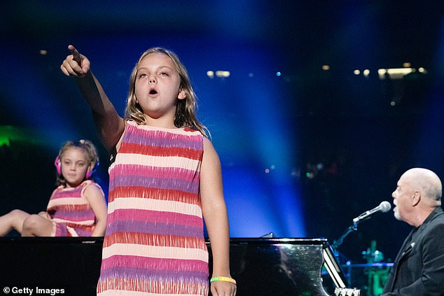 For her historic 150th show at the world's most famous stadium, Della Joel took center stage for her performance with her father at the piano and her sister sitting in the back, dressed in an identical minidress.