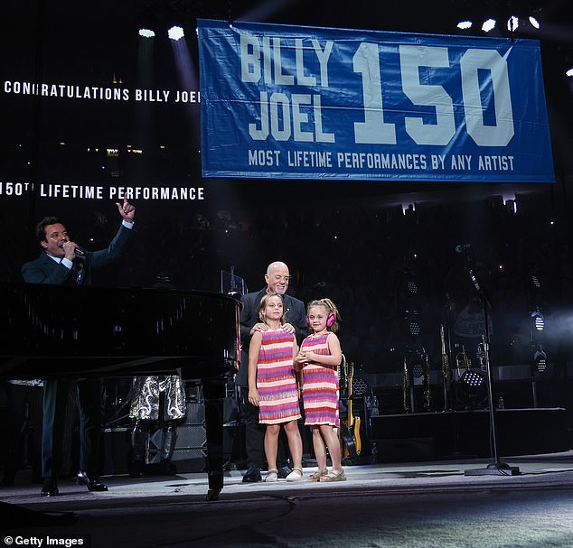 The music paused momentarily as Jimmy Fallon and Joel's daughters helped unveil the new banner marking his 150-show milestone.