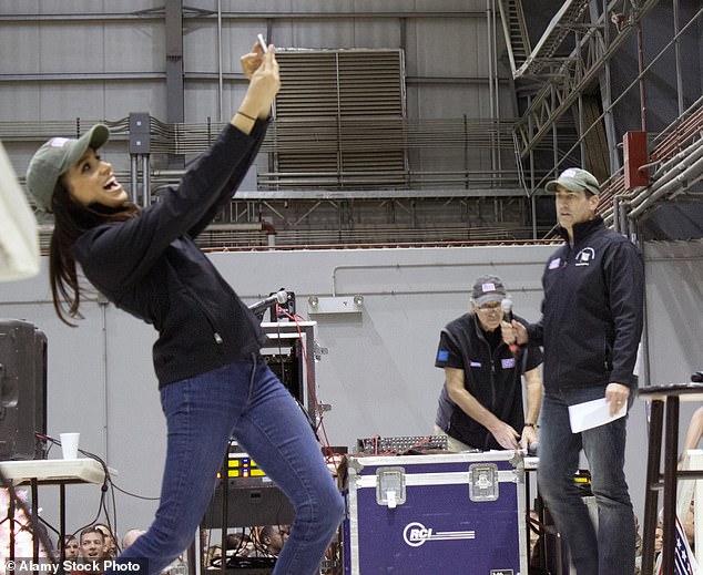 Meghan Markle, left, takes a selfie with the audience of soldiers as comedian Rob Riggle looks on during the USO Holiday troop visit at Bagram Air Field December 9, 2014 in Afghanistan