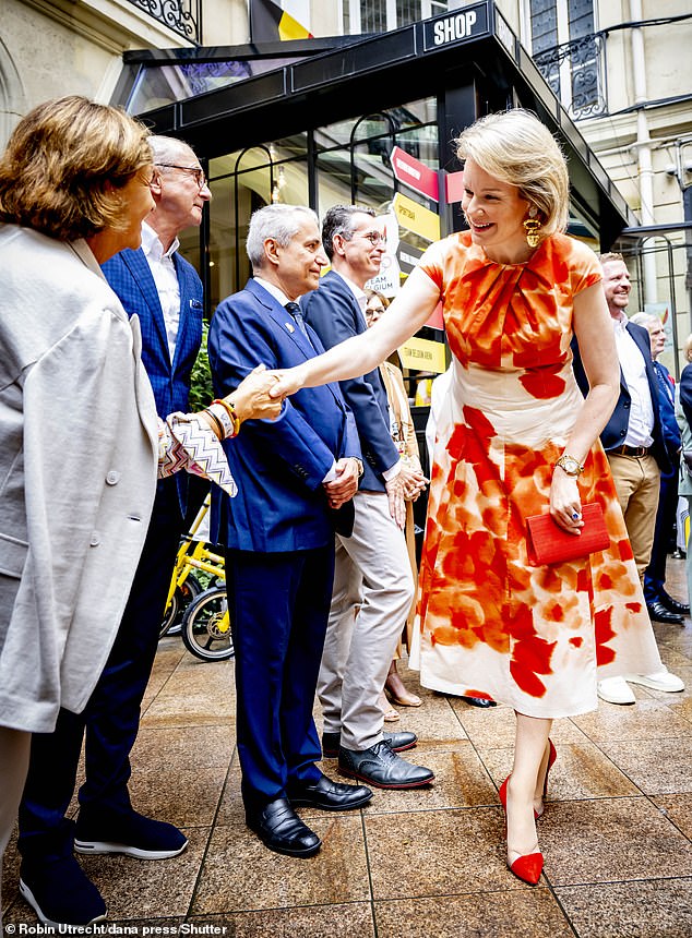 The mother of four opted for an orange and white floral summer dress which she paired with vibrant red stilettos.