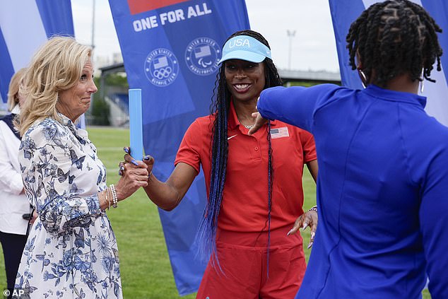 Jill Biden, left, learns proper baton passing technique from women's relay head coach Mechelle Freeman, center