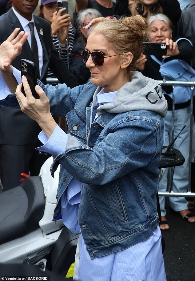 Leaving her hotel, Celine was seen with her phone in hand taking photos and videos of her fans as she reportedly prepares to make her comeback during tonight's Olympic events.