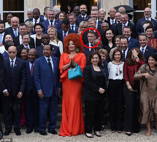 The striking ensemble makes it almost impossible to see Macron standing right behind her.