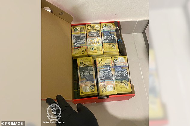 Police have provided an image showing riot squad officers breaking down the door as they begin their search. They have also released an image of $50 bills stacked inside a cardboard box.