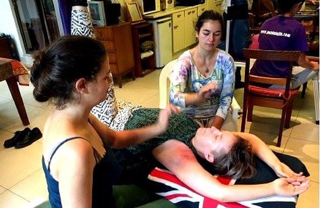 Two women perform payada on a woman by slapping her arms while she lies down.