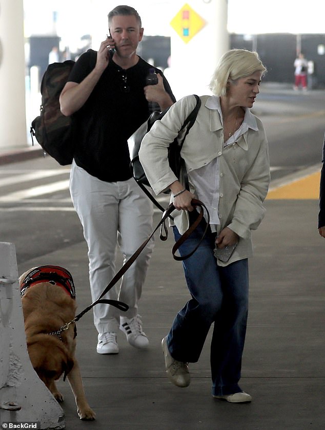 She wore a white blouse and a cream-colored sweater that was partially buttoned in the front, as well as denim jeans.