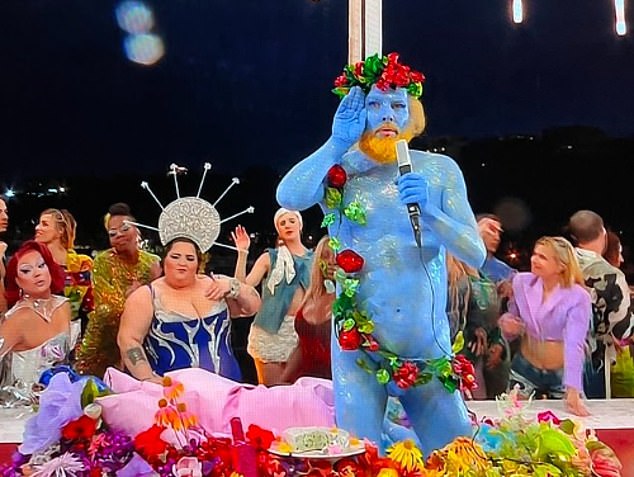 An artist painted blue and covered in flowers and fruit, representing the Greek god Dionysus, sang in French.