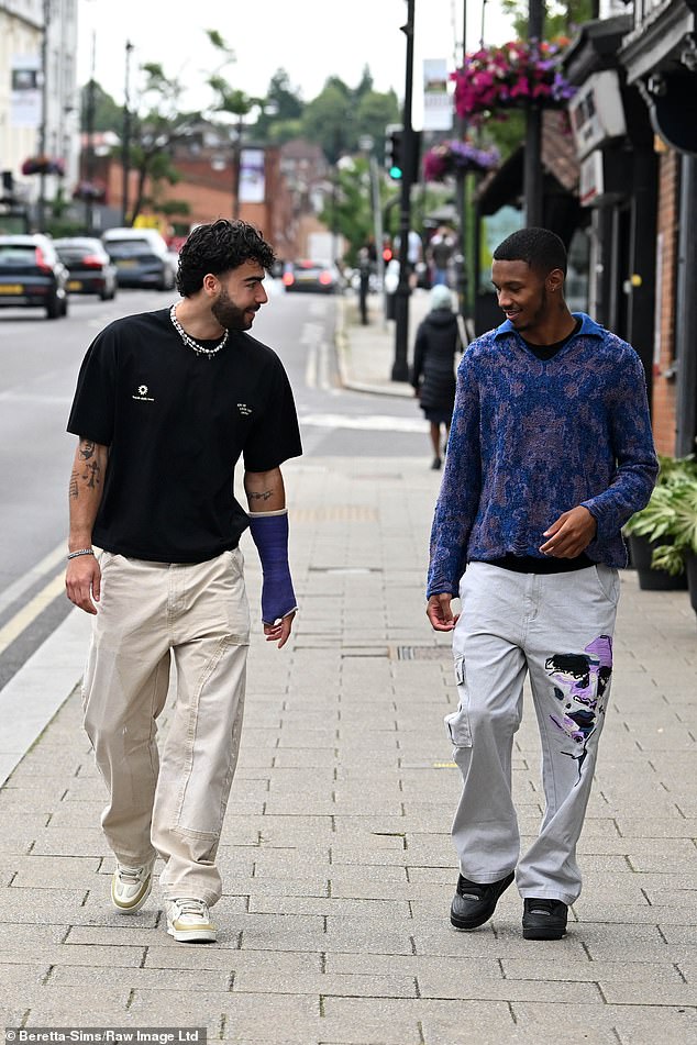 Sam wore a casual black T-shirt and cargo pants, while Roman wore a printed sweater.