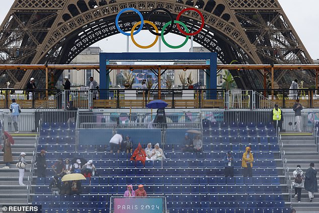 Fans wear raincoats as they wait for the opening ceremony to begin.