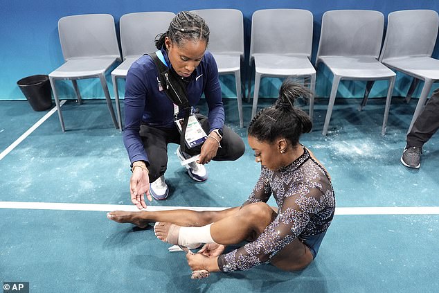 Biles has her ankle taped after competing on the uneven bars during the qualifying round.