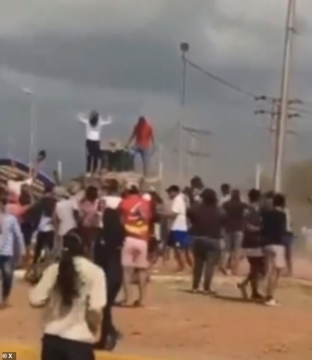 Large crowds cheer and raise their hands in the air after the statue falls.