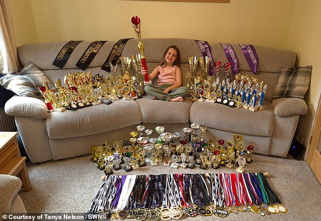 Star dancer Amelia is pictured with all her medals and trophies at just six years old.