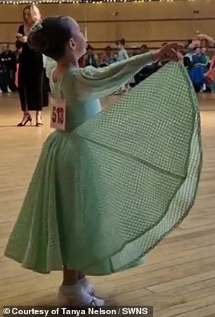 Amelia is seen holding her dress while performing a routine.