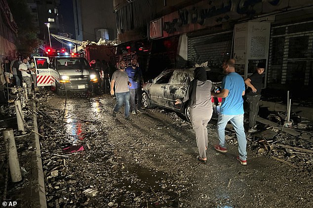 People walk near the building that was hit by an Israeli airstrike in the southern suburbs of Beirut.